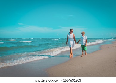 happy mother with son walk on beach, family at sea