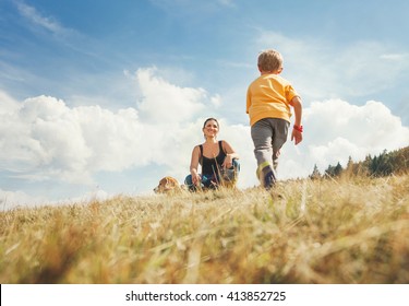 Happy Mother And Son Walk On The Golden Field With Dog