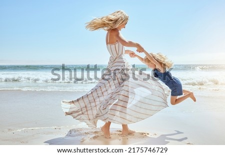 Happy mother swinging and spinning cute daughter in circles by the arms at the beach. Playful, energetic and joyful kid having fun while bonding with mom on sunny summer vacation outdoors
