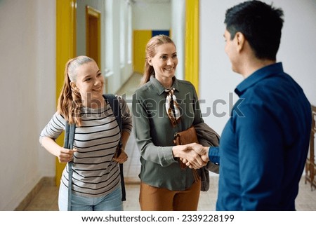 Happy mother of teenage girl shaking hands with high school principal in a hallway. Stock foto © 