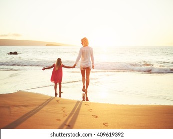 Happy Mother And Young Daughter On The Beach At Sunset