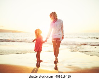 Happy Mother And Young Daughter On The Beach At Sunset