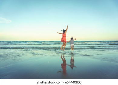 Happy Mother And Young Daughter On The Beach At Sunset.