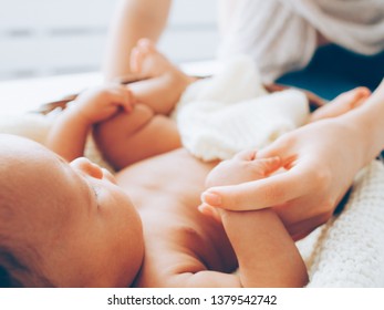 Happy Motherhood. Mother Pampering Her Newborn Baby. Closeup Of Infant Child Lying In Cradle.