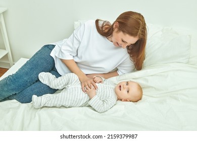 Happy Motherhood. Portrait Of A Happy, Laughing Mother Lying On A Bed With A Cute Baby. Mother And Child.