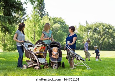 Happy mothers with baby strollers talking in park - Powered by Shutterstock