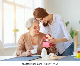 Happy Mother's Day! Adult Daughter Gives Gift And Congratulates An Elderly Mother On The Holiday 
