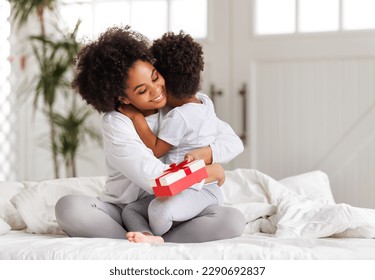 happy mother's day. african american baby daughter giving  gift box to her mom for holiday in bed at home  
 - Powered by Shutterstock