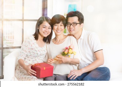 Happy Mothers Day. Asian Senior Mom Received Gift Box And Flowers From Her Young Children. Family Living Lifestyle At Home.