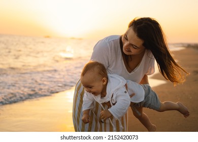 Happy Mother's Day. Beautiful Mother And Baby Play On The Beach. Mum And Her Child Together Enjoying Sunset. Loving Single Mother Hugs Cute Little Son.