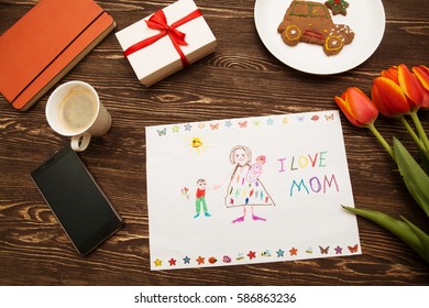 Happy Mothers Day Card Made By A Child And A Coffee Cup On A Wooden Background Of A Table.