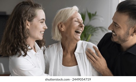 Happy Mothers Day celebration, adult siblings congratulate their happy mom with holiday, hugging, feeling love, showing support. Three male female companions colleagues enjoy joint success in office - Powered by Shutterstock