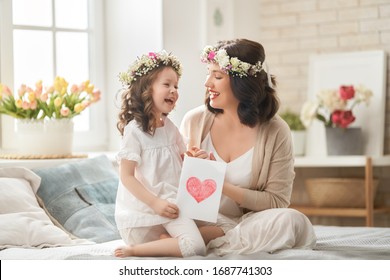 Happy mother's day! Child congratulating mom. Mum and daughter smiling and hugging. Family holiday and togetherness.                                                                                  