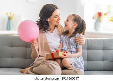 Happy Mother's Day! Child Congratulating Mom. Mum And Daughter Smiling And Holding Gift. Family Holiday And Togetherness.