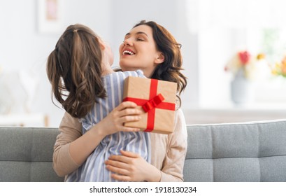 Happy Mother's Day! Child Congratulating Mom. Mum And Daughter Smiling And Holding Gift. Family Holiday And Togetherness.