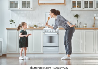 Happy mother's day! Child daughter and mom cooking and having fun in the kitchen at home. Family holiday and togetherness.