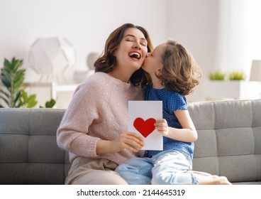 Happy mother's day. Child daughter is congratulating mom and giving her postcard. Mum and girl smiling and hugging. Family holiday and togetherness. - Powered by Shutterstock