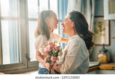 Happy mother's day. Child daughter congratulating her mother and giving her bouquet of flowers. - Powered by Shutterstock