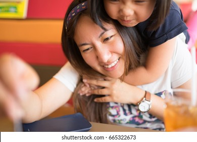 Happy Mother's Day! Child Daughter Congratulates Mom And Gives Her Cake And Postcard. Mum And Girl Smiling And Hugging In Restaurant.Family Holiday And Togetherness.