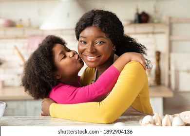 Happy Mother's Day Concept. Cute Little Black Girl Kissing And Embracing Her Happy Mom In Kitchen While They Cooking Together, Loving African Child Enjoying Spending Time With Mommy, Closeup