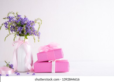 Happy Mothers Day Concept. Gift Box With Purple Flower On White Wooden Table Background.