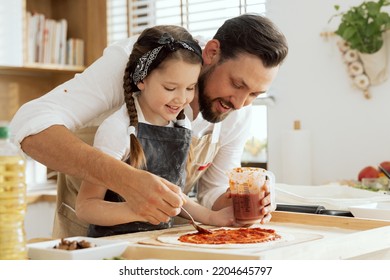 Happy mother's day handsome father with young daughter applying ketchup on homemade dough for pizza preparing surprise for lovely mother. - Powered by Shutterstock