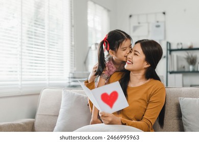 Happy mother's day. Mother receiving a handmade card from her daughter in living room at home. - Powered by Shutterstock