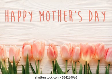 Happy Mother's Day Text Sign On Pink Tulips On White Rustic Wooden Background. Greeting Card Concept. Sensual Tender Women Image. Spring Flowers Flat Lay