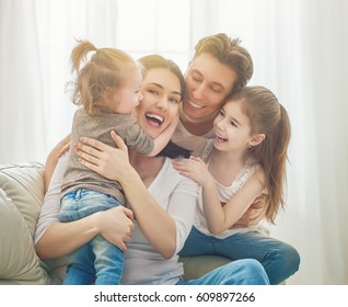 Happy mother's day! Two children daughters with father congratulate mom. Mum, dad and girls laughing and hugging. Family holiday and togetherness.