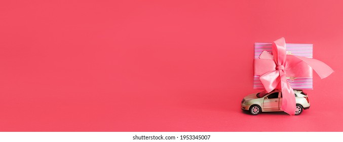 Happy Mother's Day Or Women's Day. Pink Gift Box On Toy Car On Pink Background. A Greating Card Or Banner For A Website Or A Sale In A Store. Copy Space. Mock Up.