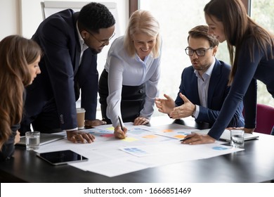 Happy motivated diverse businesspeople work together cooperate at business office meeting, smiling multiracial colleagues discuss ideas financial project at boardroom briefing, collaboration concept