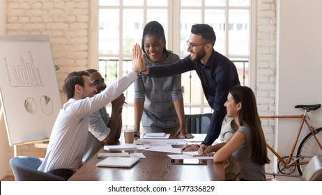 Happy motivated male colleagues executives team give high five at multiracial group meeting celebrating shared win, good teamwork result, corporate success victory thanking for help support in work - Shutterstock ID 1477336829