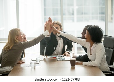 Happy motivated multiracial team giving high five at meeting, diverse group of colleagues join hands together celebrating corporate growth, successful teamwork, unity help support in business concept