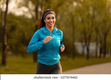 Happy motivated sportswoman running in the park and looking at camera.  - Powered by Shutterstock