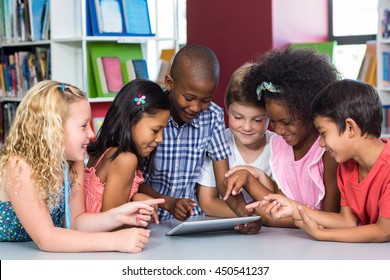 Happy Multi Ethnic Children Using Digital Table In Library