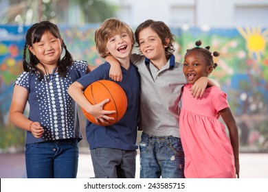 Happy Multi Ethnic Elementary Kids Playing Basketball In School Courtyard