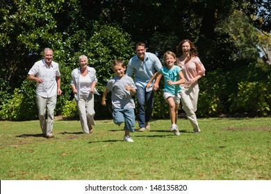 Happy Multi Generation Family Running Towards Camera In The Park On Sunny Day