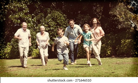 Happy Multi Generation Family Running Towards Camera In The Park On Sunny Day