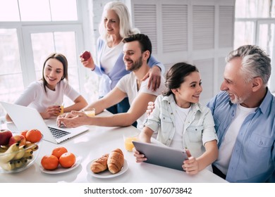 The Happy Multi Generation Family Sitting With A Laptop And The Tablet