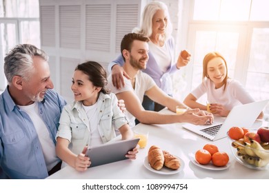 The Happy Multi Generation Family Sitting With A Laptop And The Tablet