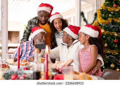 Happy Multi Generation Family Wearing Santa Hats, Taking Selfie. Family Christmas Time And Festivity Together At Home.