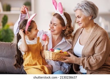 Happy multi generational family grandmother mother and daughter in bunny ears laugh and play with eggs at home in a cozy living room during preparation for   Easter holiday - Powered by Shutterstock