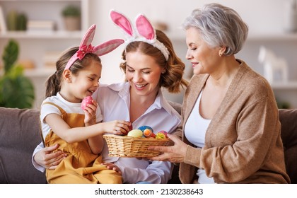 Happy multi generational family grandmother mother and daughter in bunny ears laugh and play with eggs at home in a cozy living room during preparation for   Easter holiday - Powered by Shutterstock