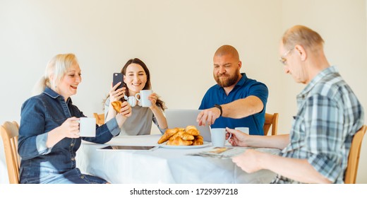 Happy Multi Generational Family Reading News In The Morning While Having Breakfast