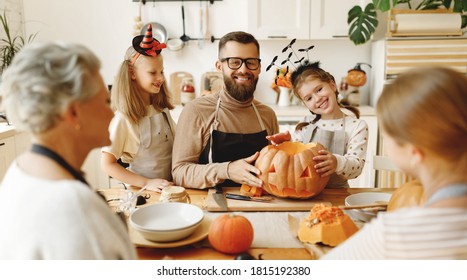 Happy Multi Generational Family Smiling And Carving Jack O Lantern From Pumpkin While Gathering Around Table During Halloween Celebration
