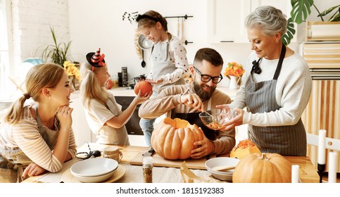 Happy Multi Generational Family Smiling And Carving Jack O Lantern From Pumpkin While Gathering Around Table During Halloween Celebration
