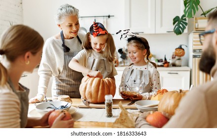 Happy Multi Generational Family Smiling And Carving Jack O Lantern From Pumpkin While Gathering Around Table During Halloween Celebration
