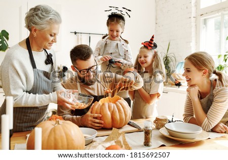 Happy multi generational family smiling and carving jack o lantern from pumpkin while gathering around table during Halloween celebration Foto stock © 
