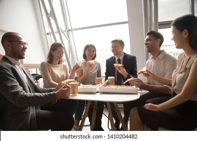 Happy Multicultural Company Staff Workers Group Business Team Having Fun Eating Pizza Together In Office, Cheerful Diverse Employees Talk Laugh Share Lunch Food Meal Enjoy Party At Work Sit At Table