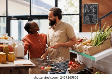 Happy multicultural couple browsing in sustainable eco friendly store. African american woman and caucasian man with a basket searching bio food products for a healthy lifestyle. - Powered by Shutterstock